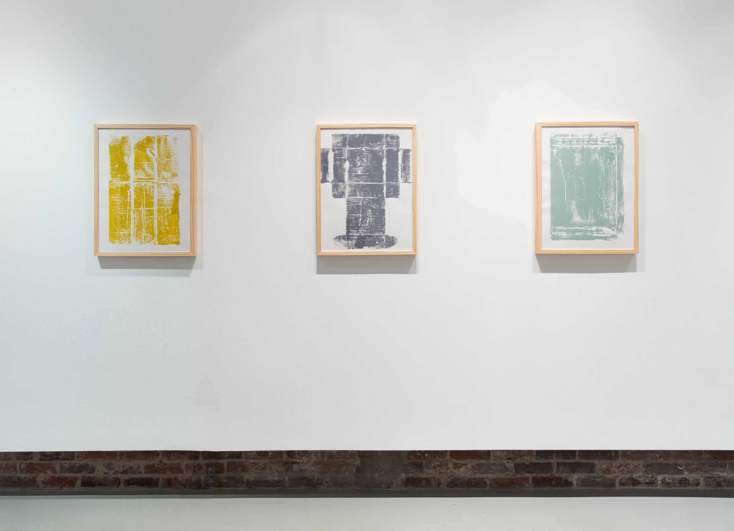 Three framed monoprints of cardboard boxes on the wall
