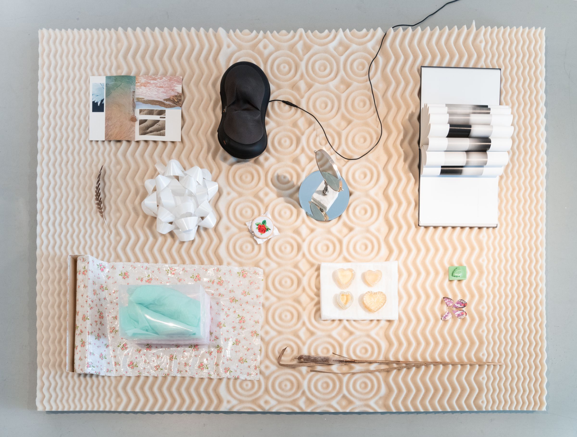 Aerial view of tan mattress topper with objects arranged on top of it