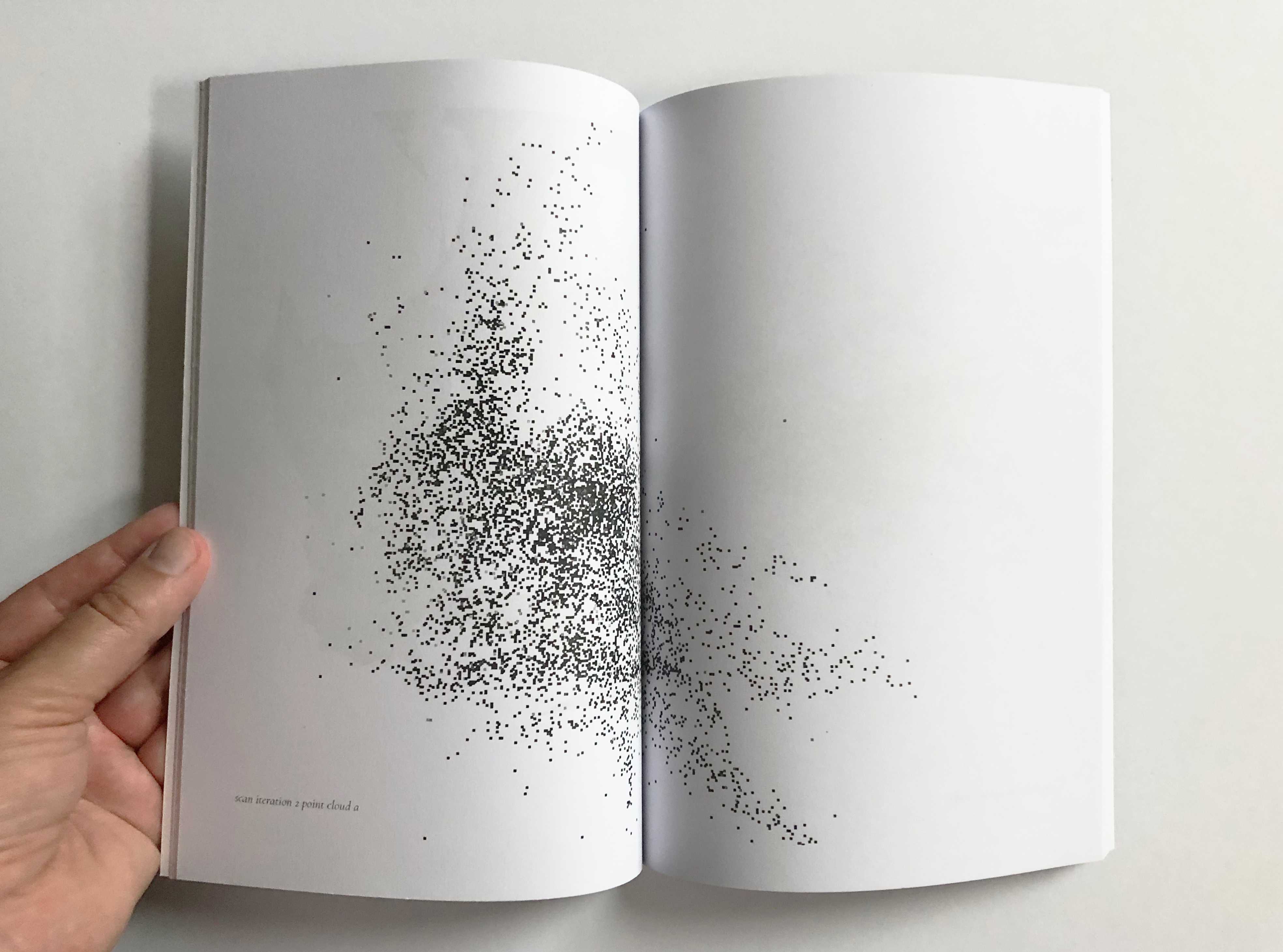 Hand holding book open to two pages with dot map