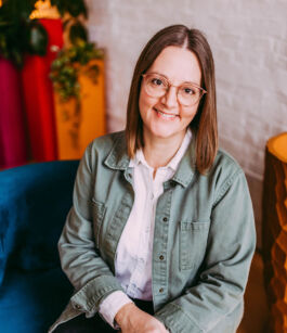 White woman with brown hair and glasses smiling directly at the camera