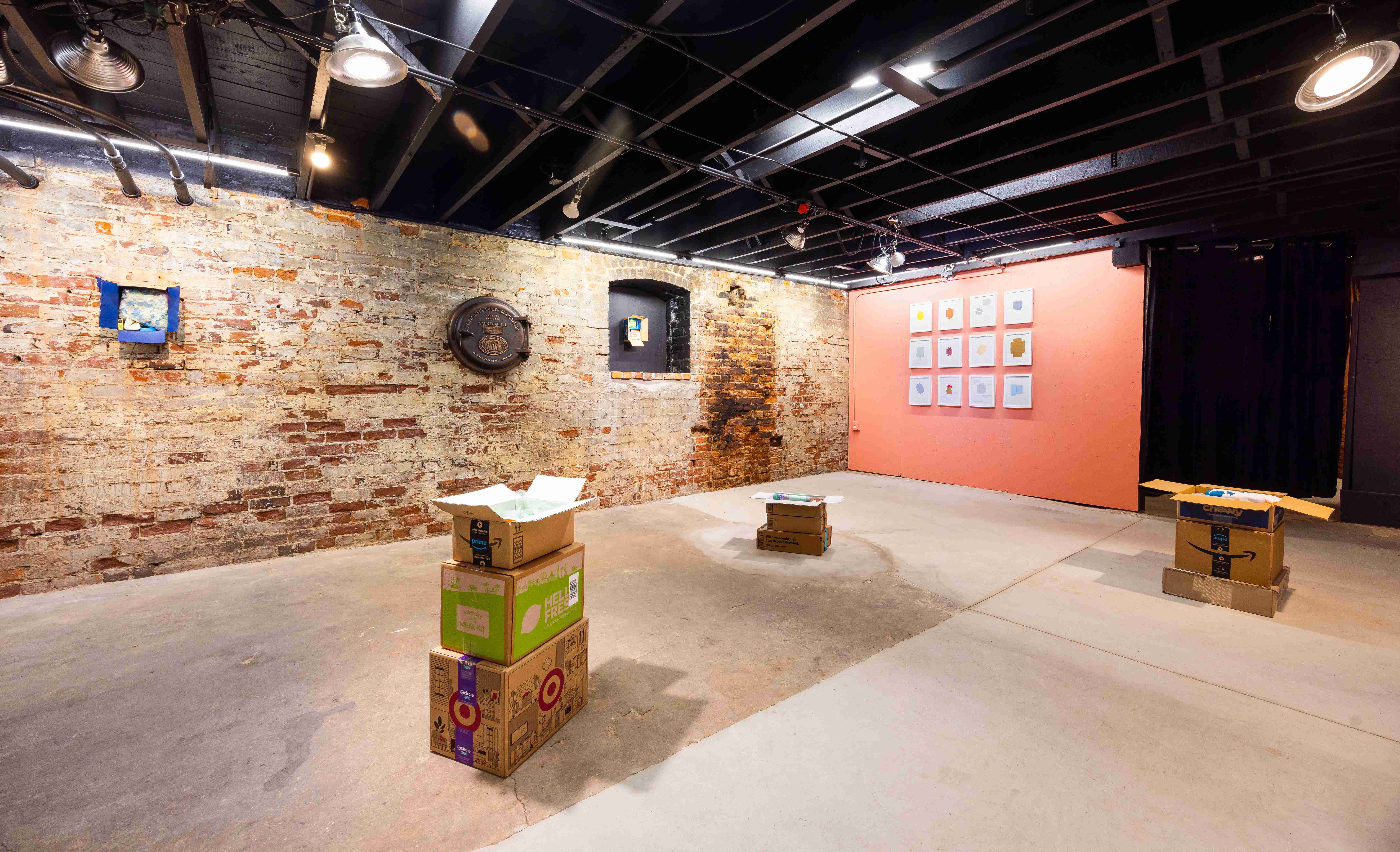 Industrial gallery space with exposed brick walls and concrete floors displaying sculptures and drawings