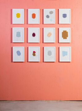 Grid of framed drawings on a coral-painted wall