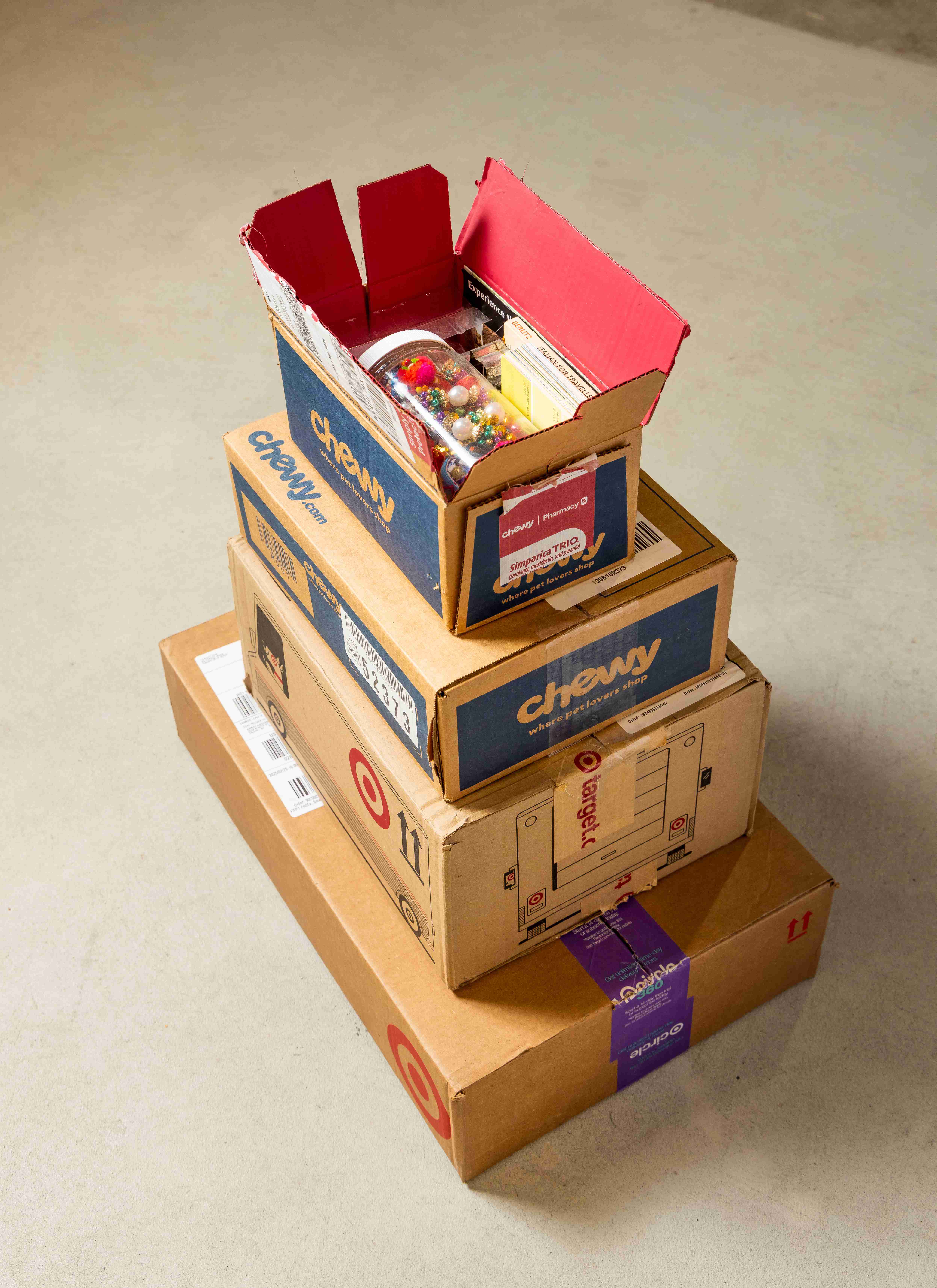 Stack of cardboard boxes with top one painted bright pink and filled with colorful objects