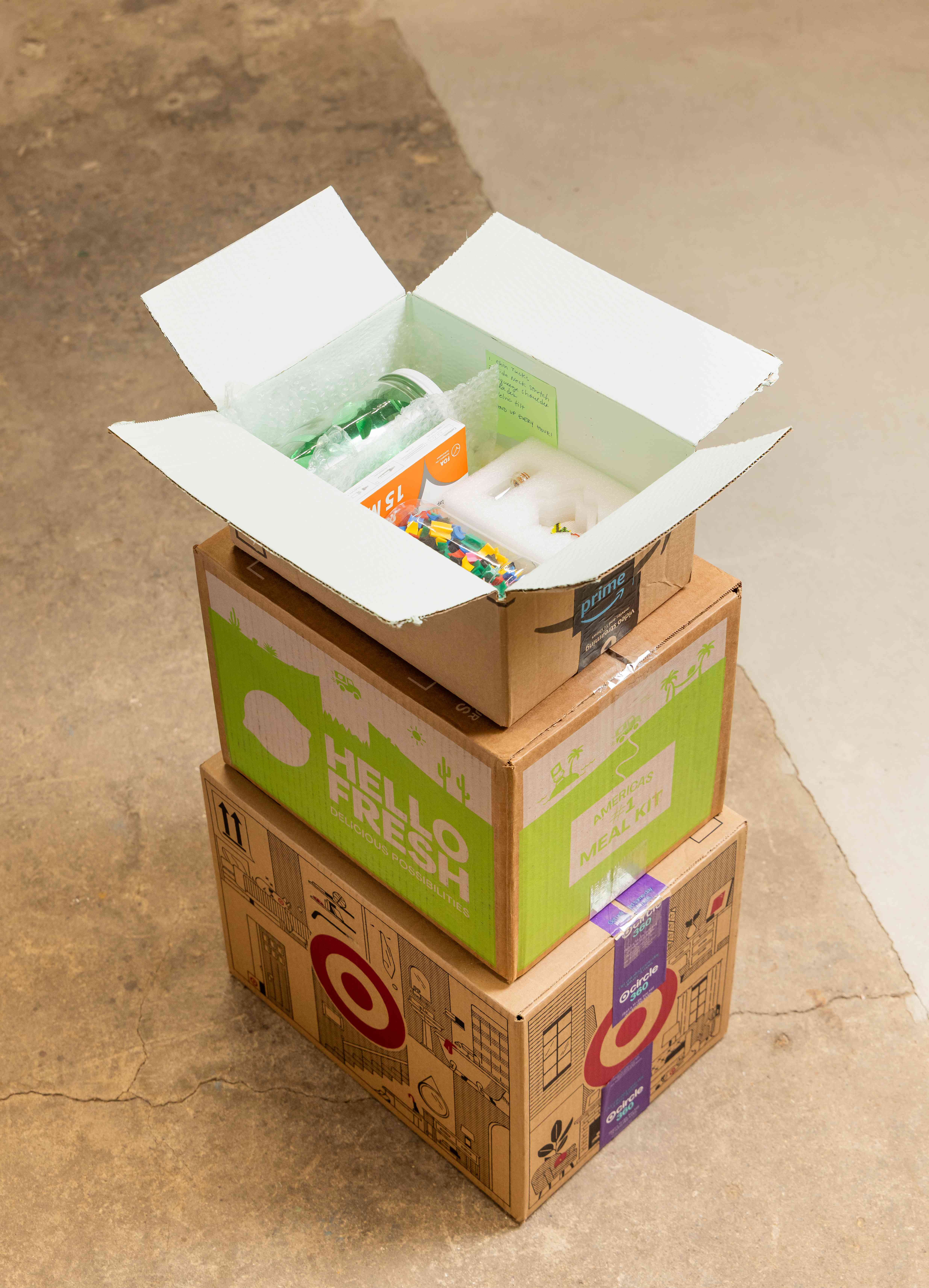 Stack of cardboard boxes with the top one painted light blue on the inside and filled with colorful objects