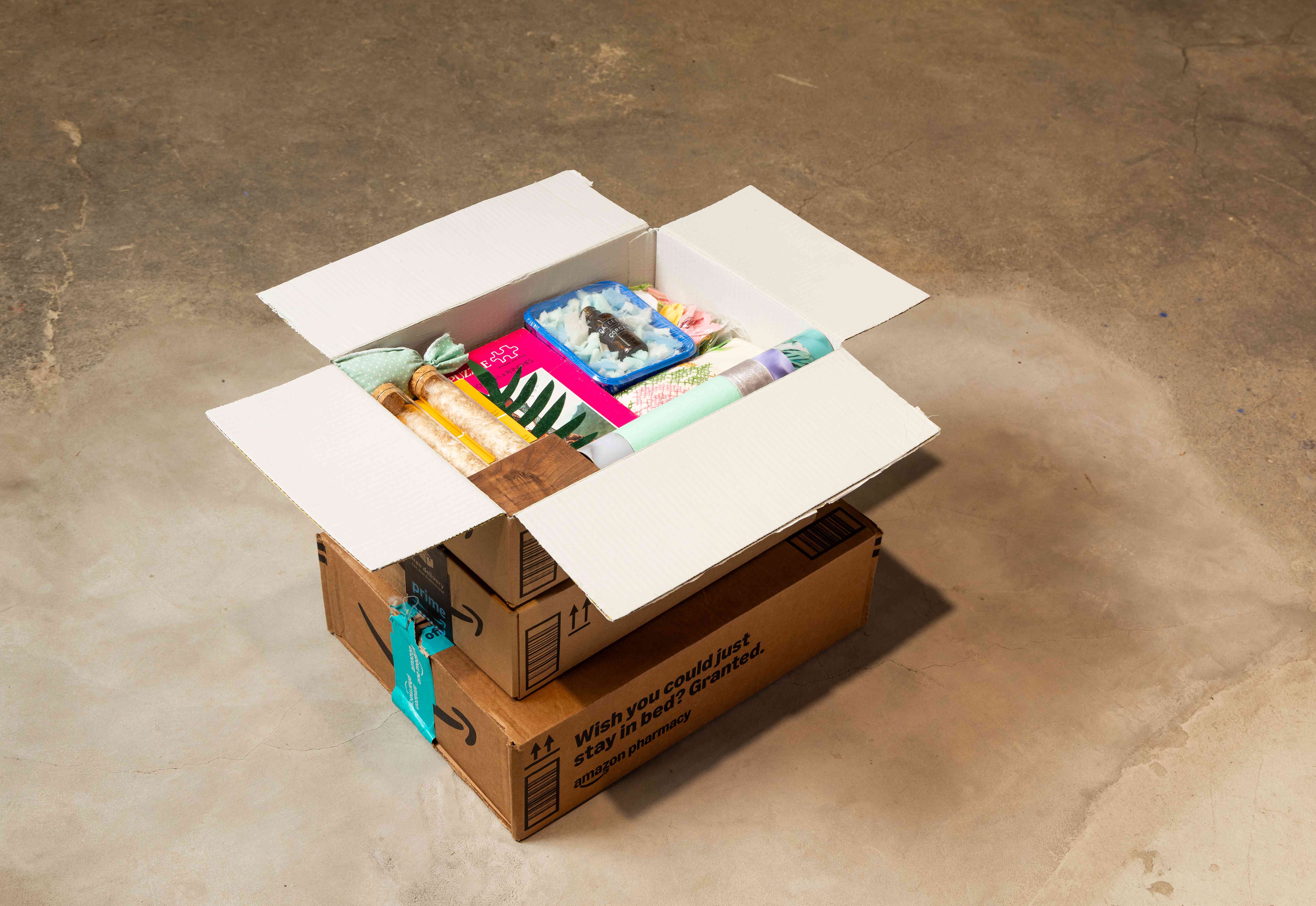 Cardboard boxes stacked on top of each other with the top one painted gray inside and filled with colorful objects
